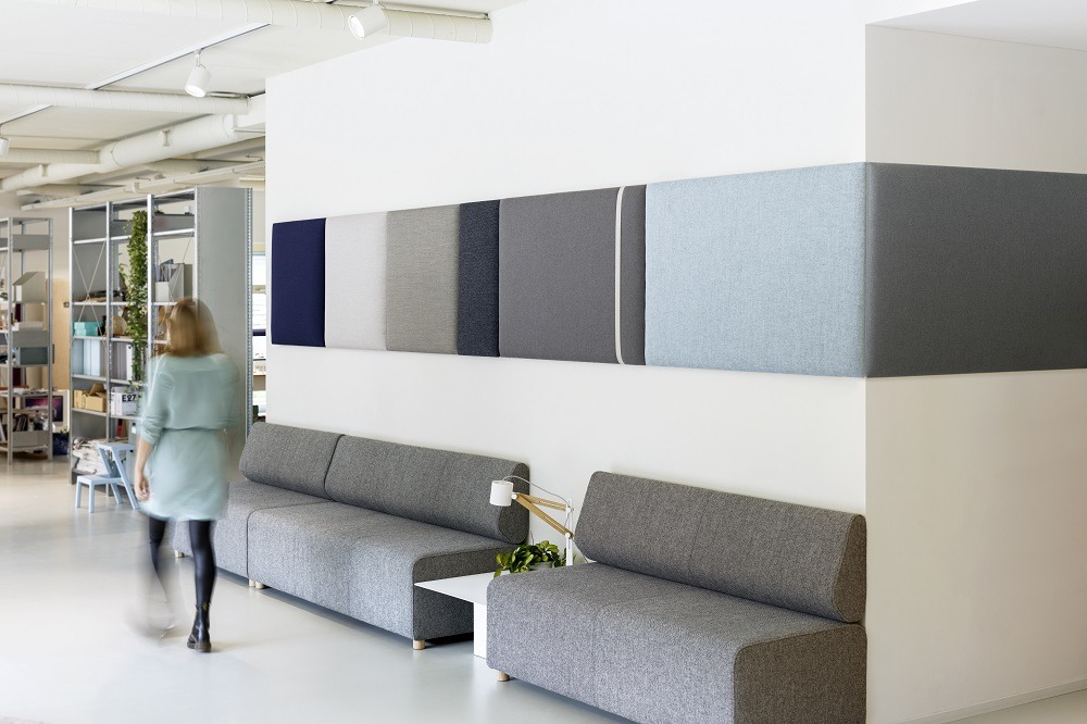 Büro mit Cascando Pillow Grid Wandpaneelen in verschiedenen Farben über grauen Sofas.