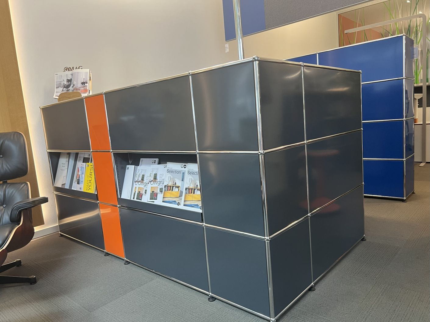 Gebrauchte USM Haller Theke in Anthrazit und Orange, modulares Designmöbel mit offenen Fächern für Kataloge.
