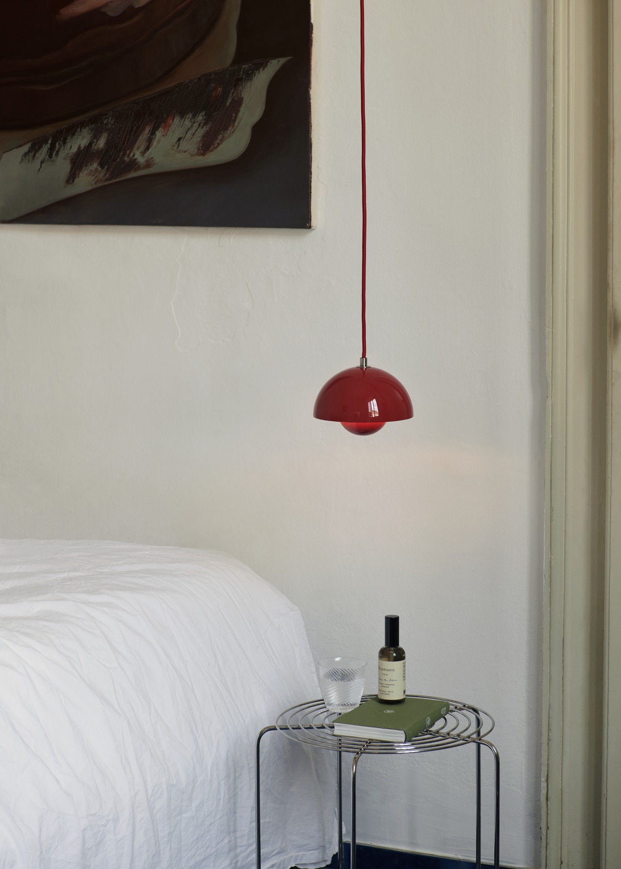AndTradition Wire Stool VP11 als Beistelltisch im Schlafzimmer mit Buch, Glas und Duft.