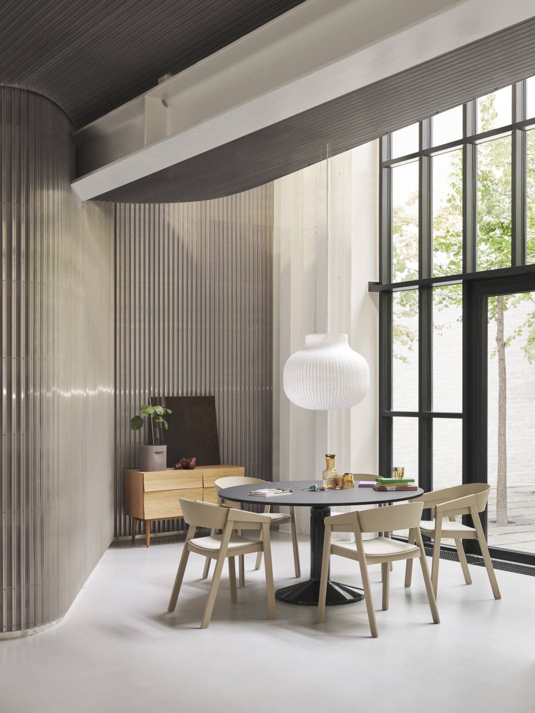 Heller Raum mit Muuto MIDST Table Esstisch, runder Tischplatte, vier Holzstühlen und großer Pendelleuchte.