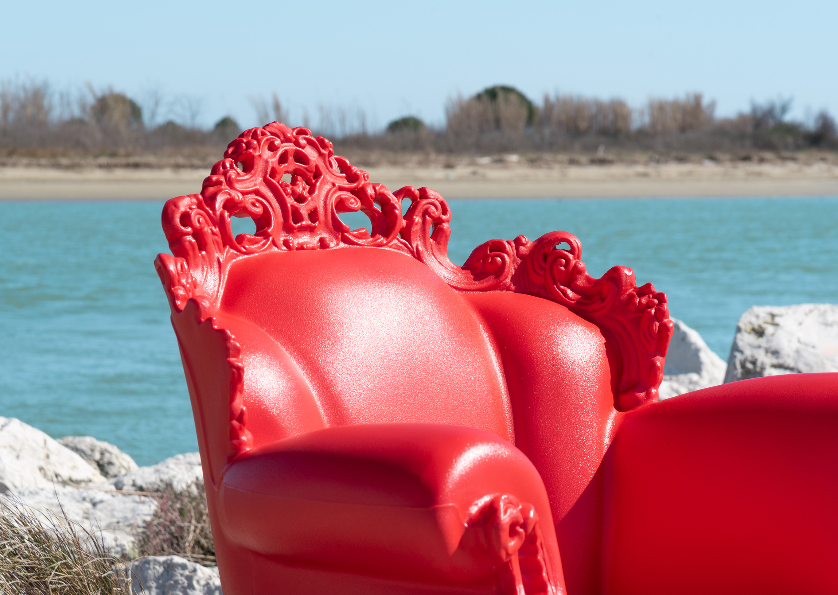 Roter Magis Proust Sessel für den Außenbereich mit filigranem Design vor blauem Wasser.