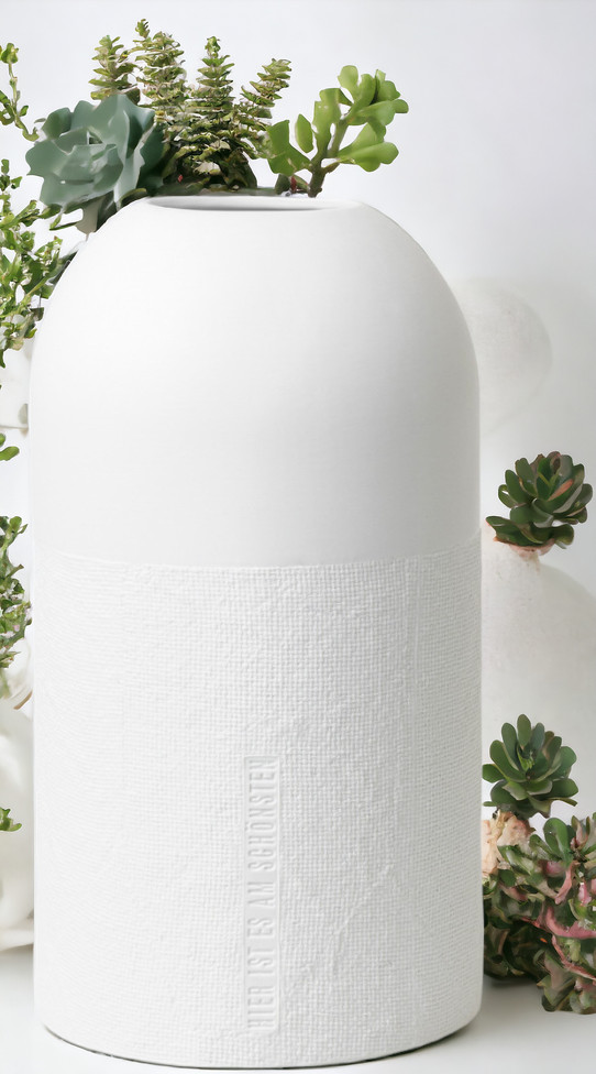 Formsprache Vase "Hier ist es am Schönsten" von Räder, weiße Dekovase mit Textur und Pflanzen.