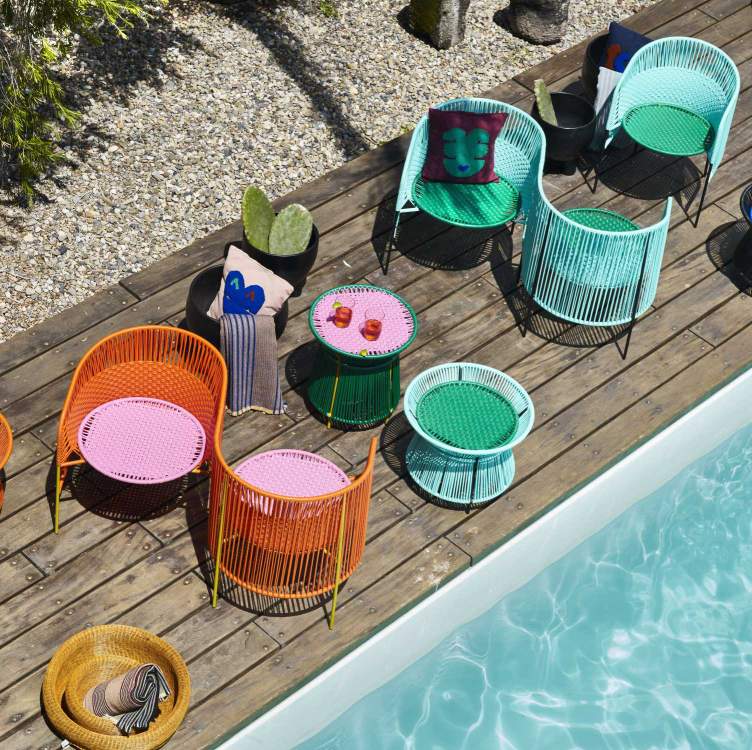 Bunte Outdoor-Möbel am Pool: Caribe Sessel und Beistelltische in Türkis, Grün, Orange und Schwarz.