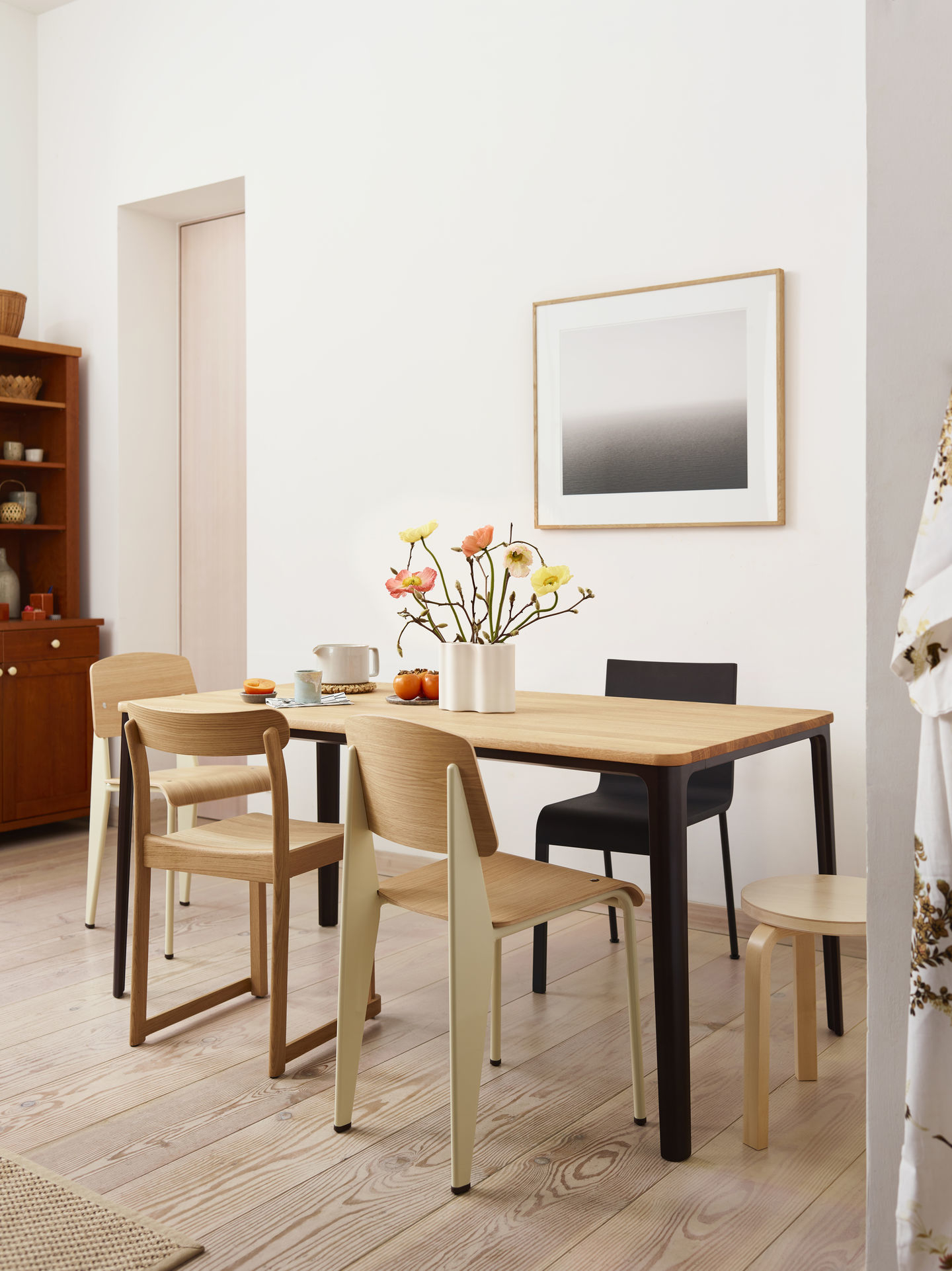 Esszimmer mit Holztisch und verschiedenen Stühlen, darunter der Vitra .03 Stuhl in Holzoptik.