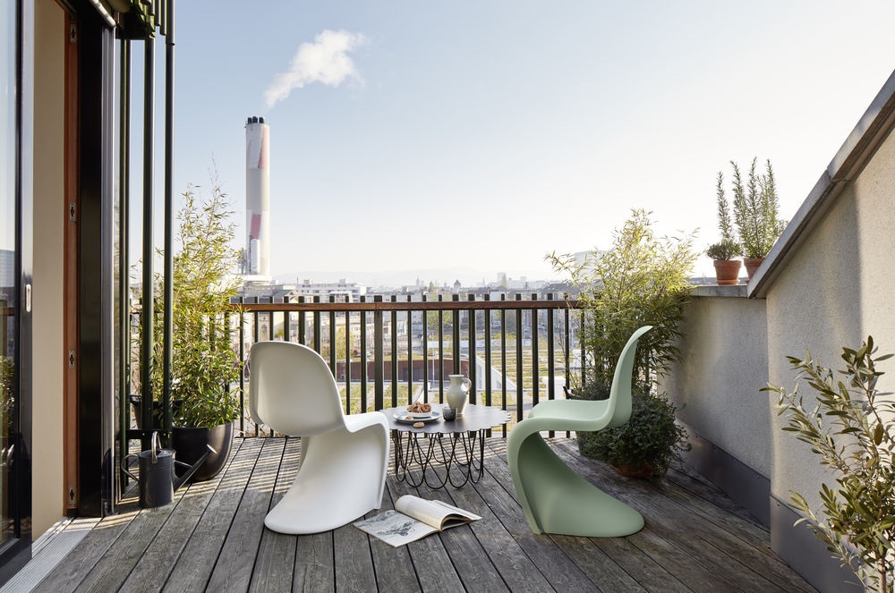 Zwei Panton Stühle in Weiß und Grün auf einem Balkon mit Tisch und Ausblick.