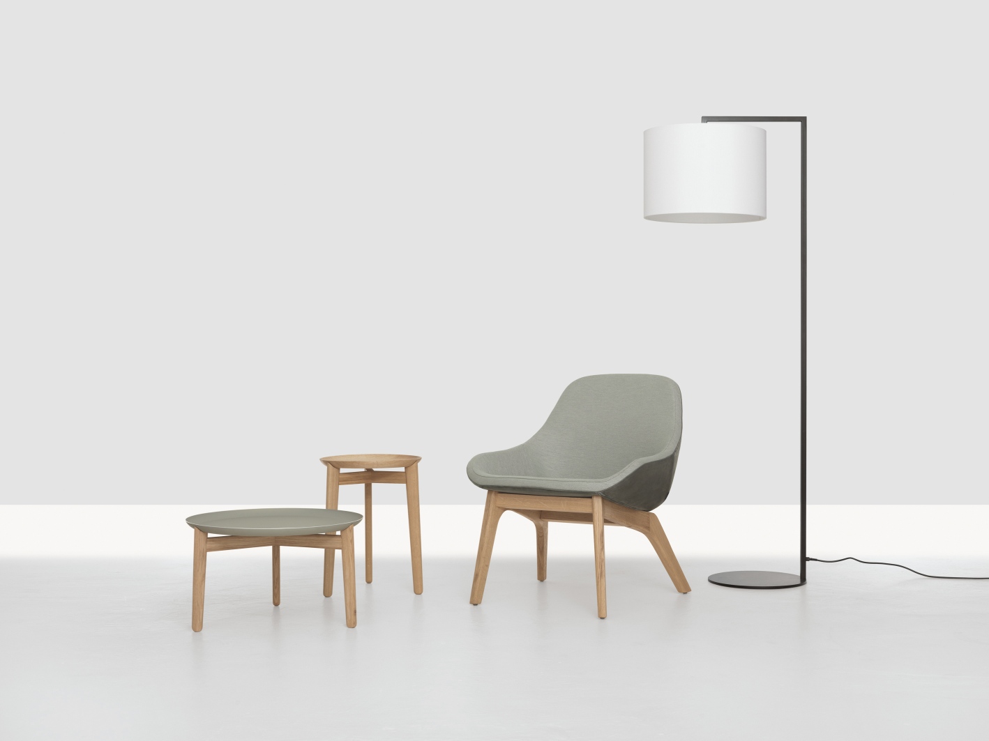 Morph Lounge Chair Sessel von Zeitraum, grauer Polstersessel mit Holztisch und Stehlampe auf weißem Hintergrund.
