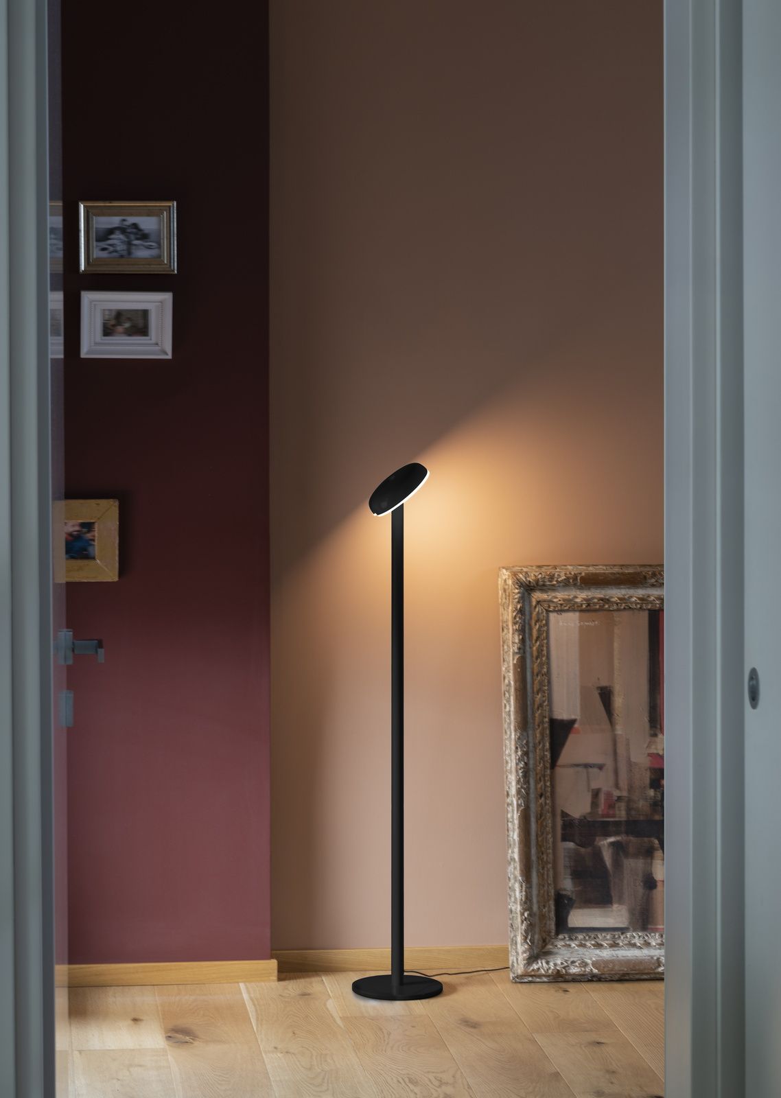 Schwarze Stehlampe mit rundem Lampenschirm spendet warmes Licht im Flur. Moderne Innenbeleuchtung für Wohnzimmer und Schlafzimmer.