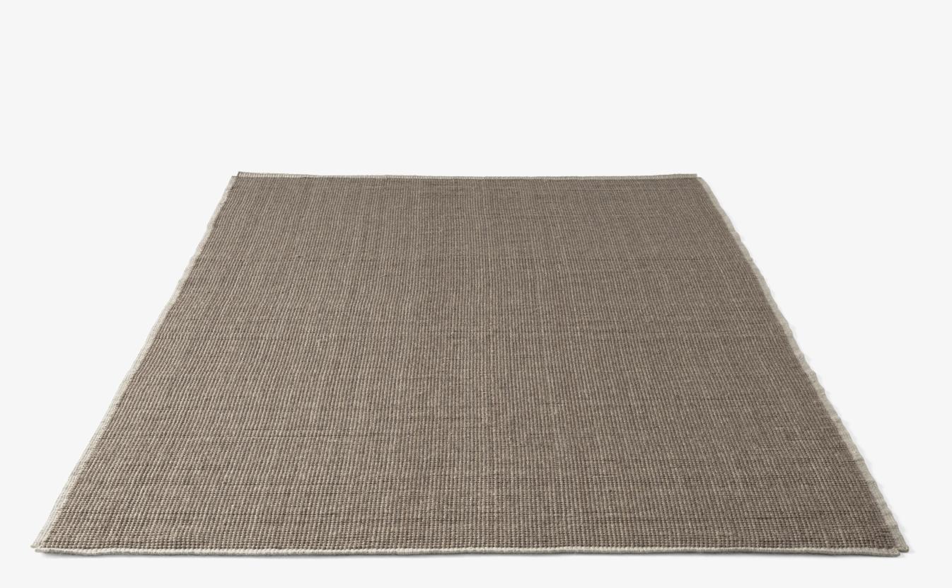 AndTradition Collect Rug SC84/SC85: Detailaufnahme des braunen Wollteppichs mit feiner Textur und hellem Rand.