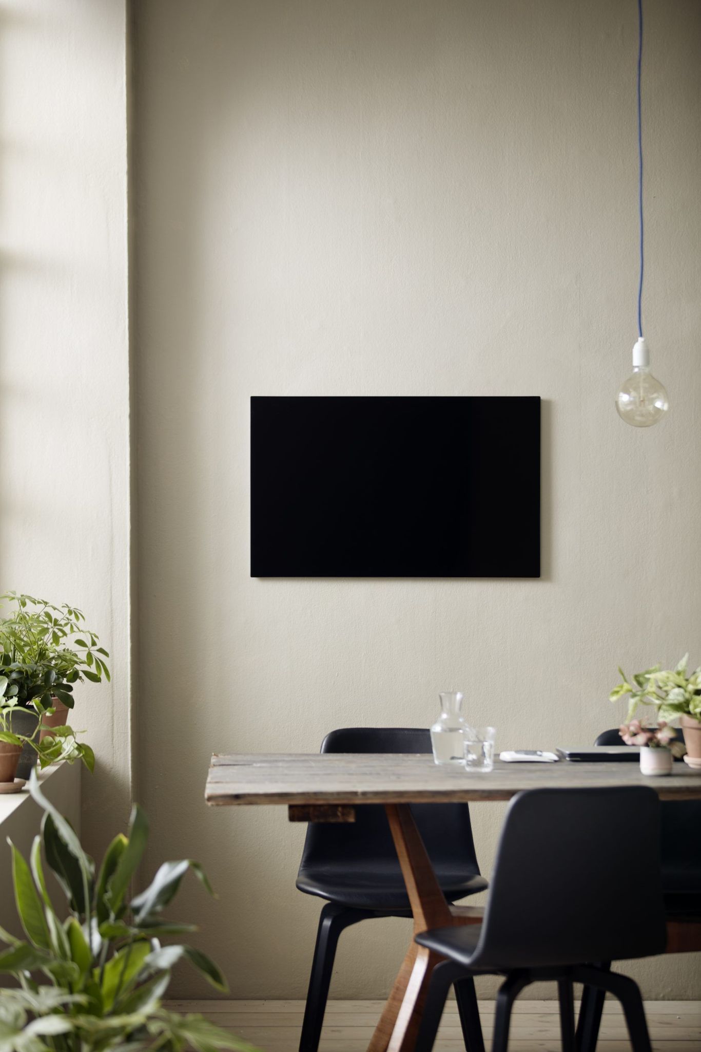 Schwarze Chat Board Classic Wand Glastafel magnetisch über einem Esstisch in einem modern eingerichteten Raum.
