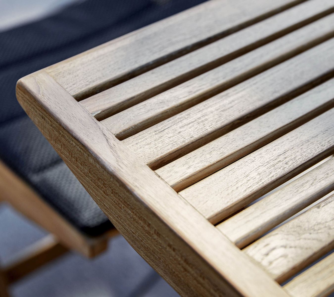 Detailaufnahme des Cane-Line Flip Klapptischs aus Teakholz mit Lattenstruktur, ideal für den Garten.