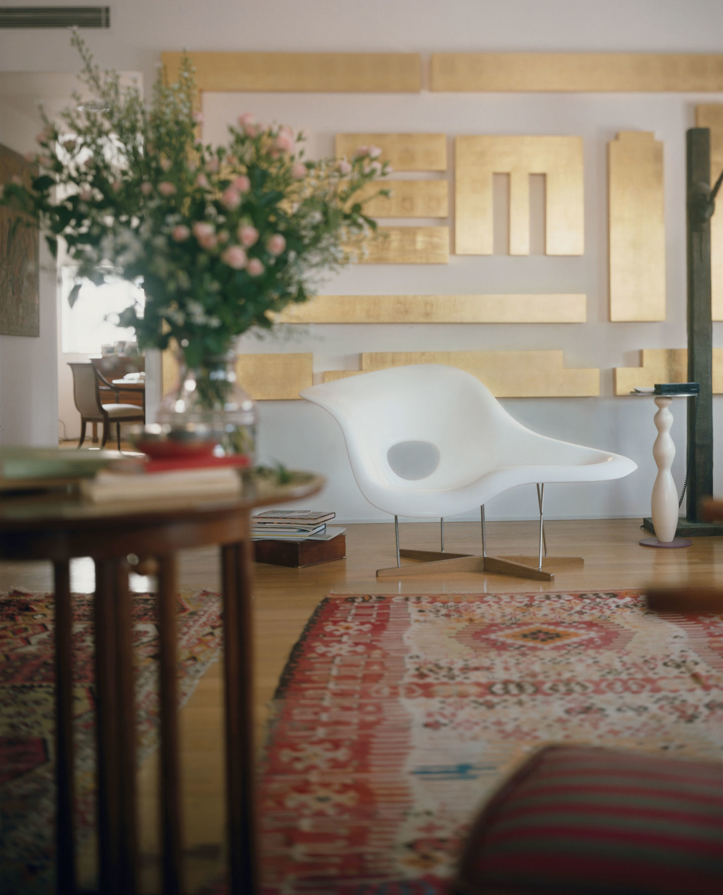 Helle La Chaise Liege von Vitra im Wohnzimmer mit Teppich und Blumenarrangement.
