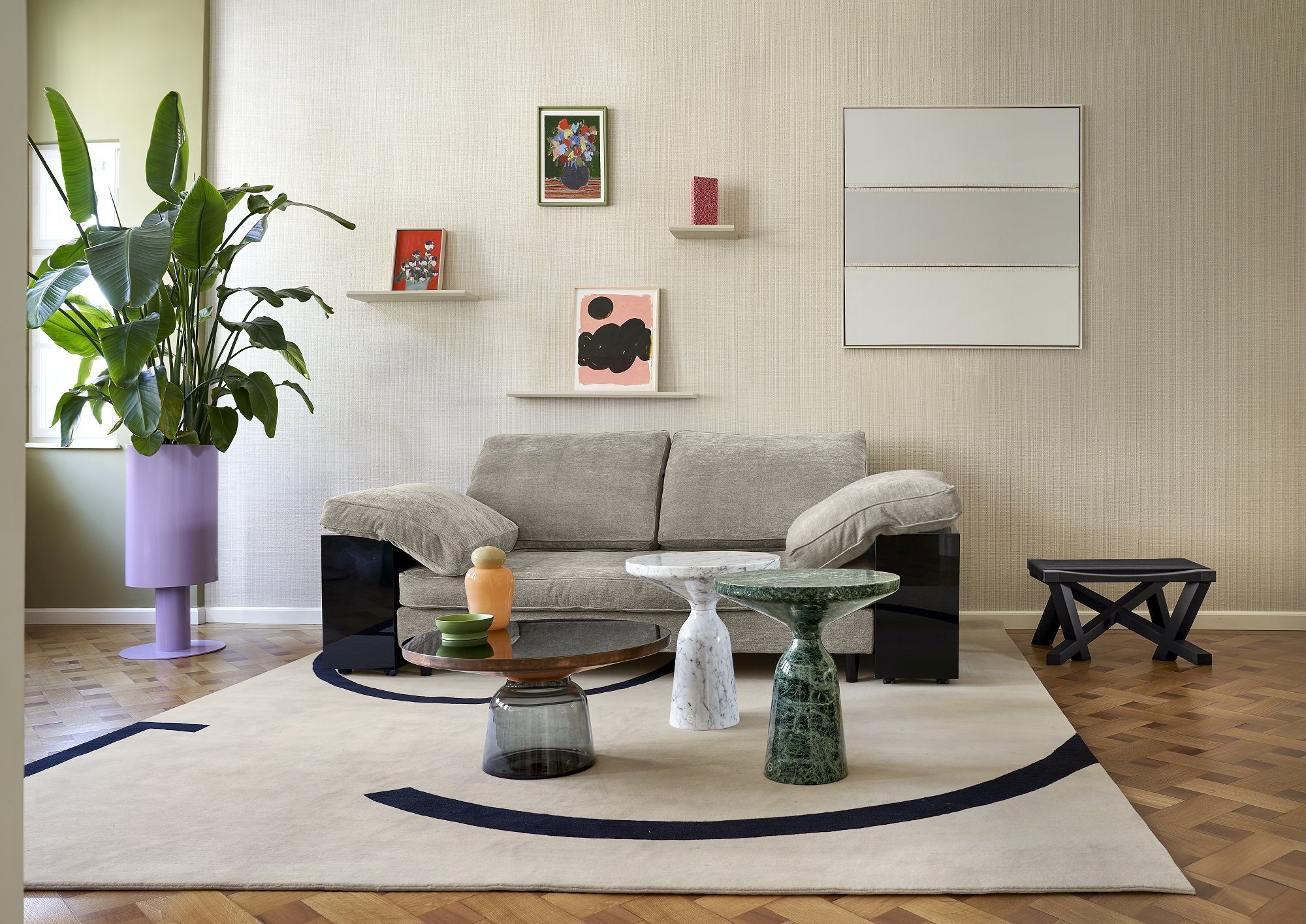 Helles Wohnzimmer mit Classicon Lota Sofa, Couchtischen aus Marmor und Glas auf gemustertem Teppich.