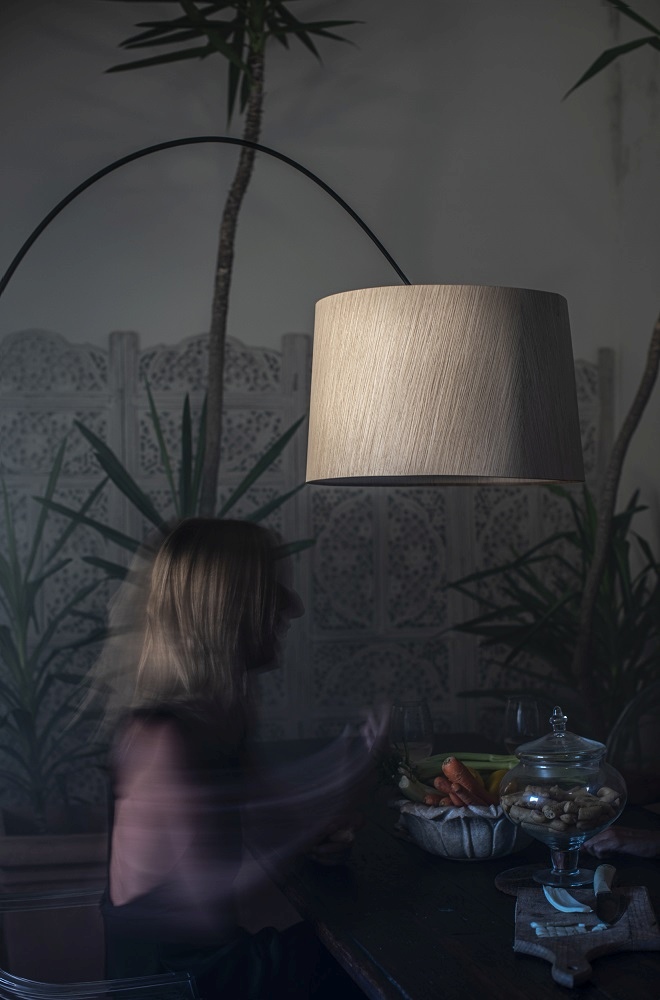 Twiggy Wood Stehleuchte von Foscarini über Esstisch mit Frau im Hintergrund.