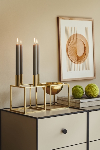 Goldener Kerzenständer mit grauen Kerzen und goldener Schale auf beigem Sideboard, moderne Dekoration.