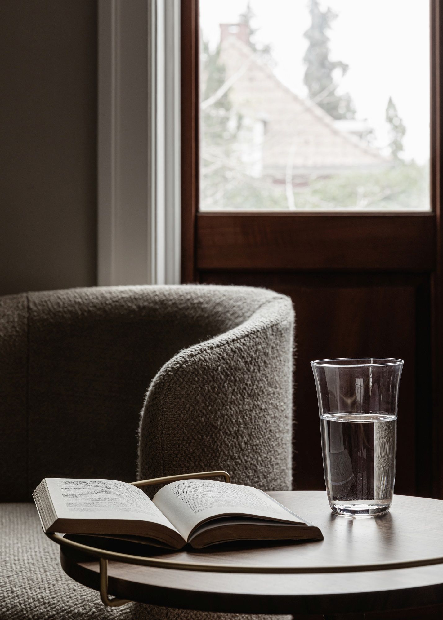 Tearoom Club Chair Sessel von Audo Copenhagen mit Buch und Wasserglas auf Beistelltisch.