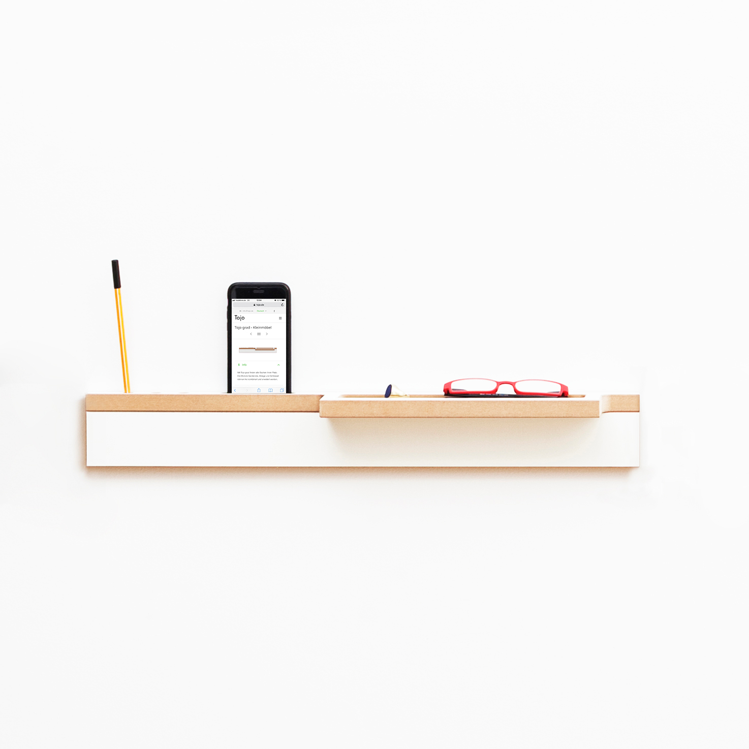 Tojo Grad Ablage: Wandregal in Weiß und Holz mit Stift, Handy und Brille.
