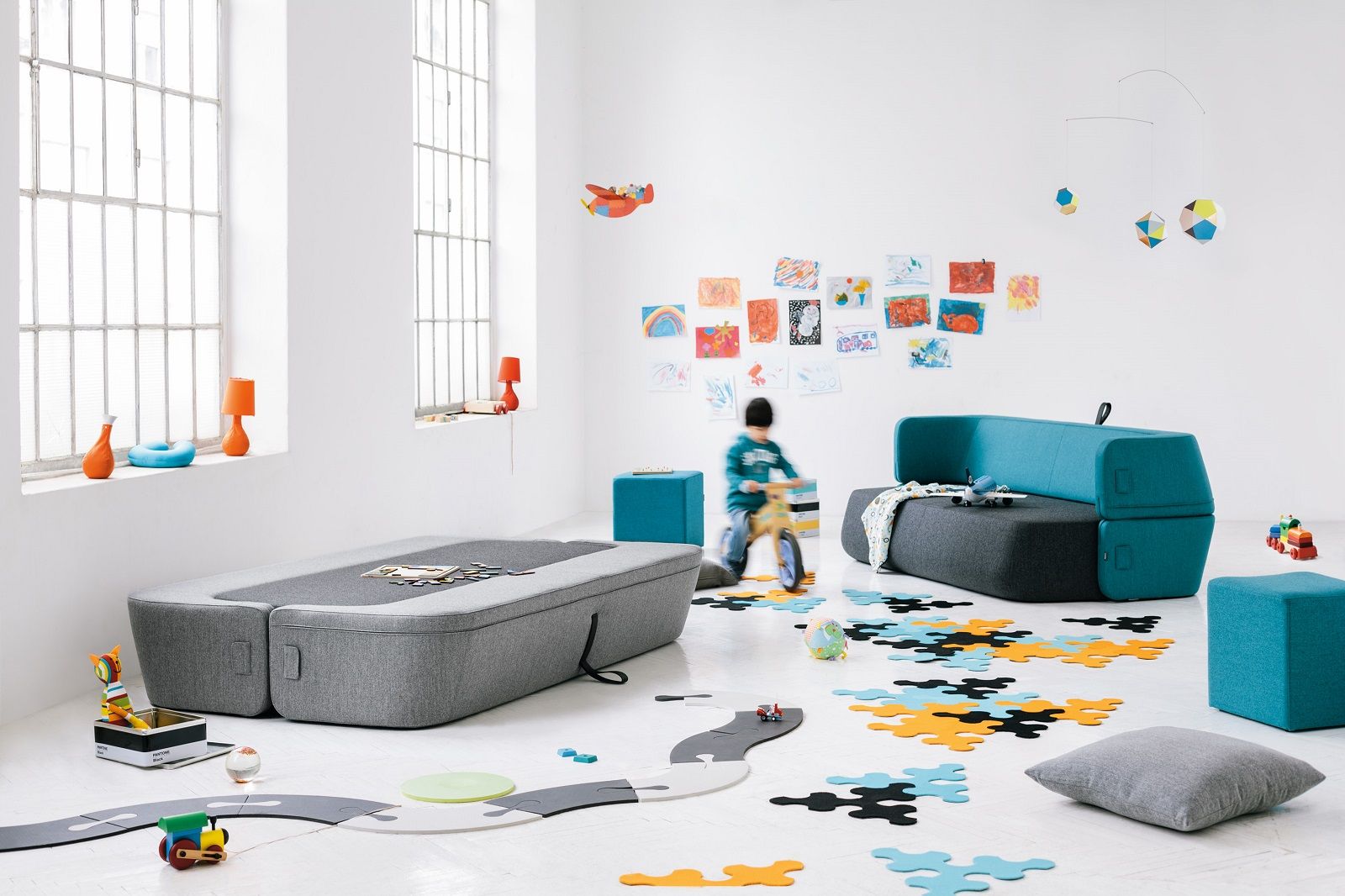 Helles Kinderzimmer mit Revolve Schlafsofa von Prostoria in Grau und Türkis, umgeben von Spielzeug.