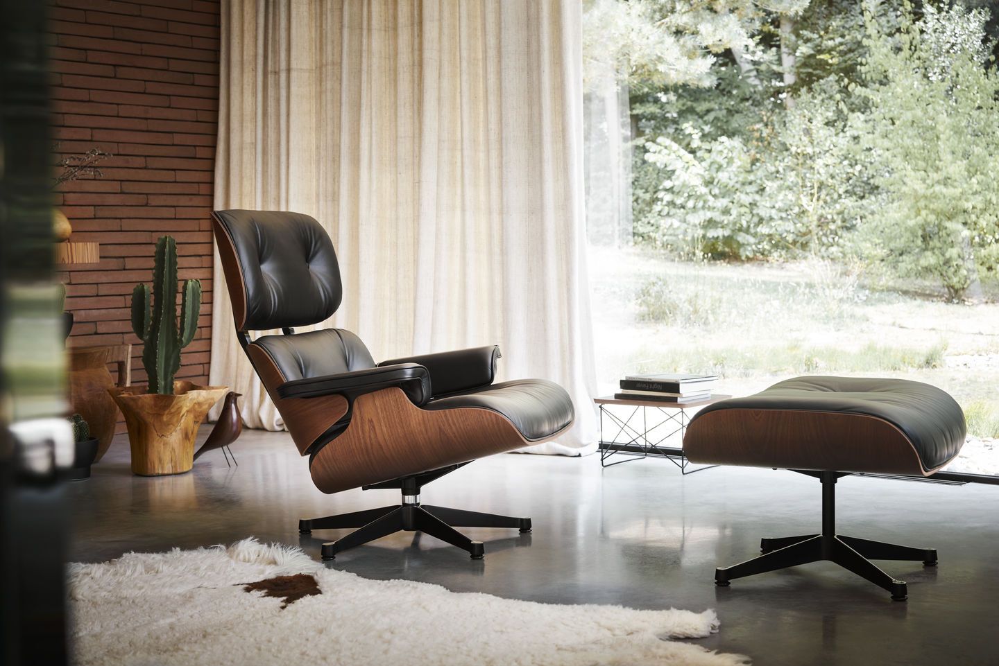 Schwarzer Ledersessel mit Fußhocker und Holzschale, modernes Design für Wohnzimmer und Büro.