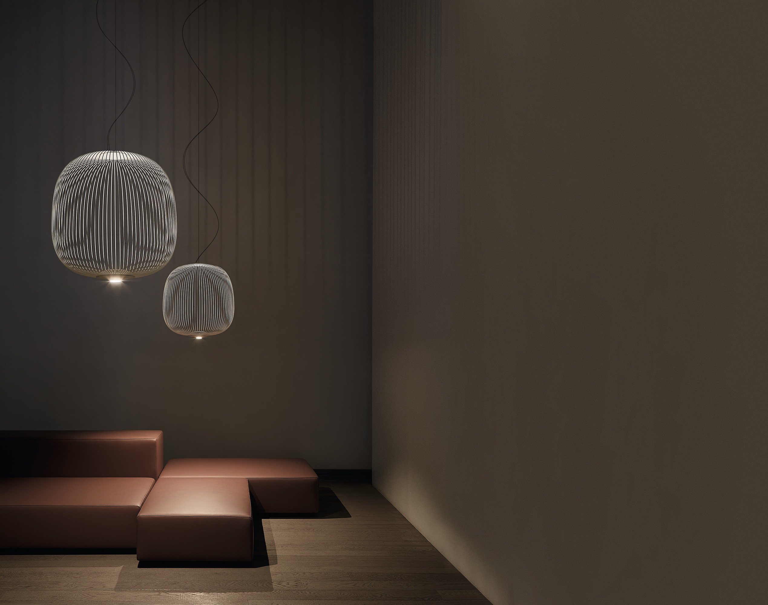 Zwei moderne Spokes 2 LED Pendelleuchten von Foscarini über braunem Ledersofa in dunklem Raum.