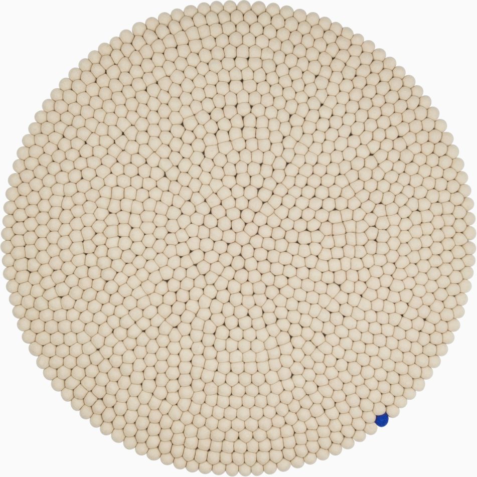 Beiger, runder Filzteppich (Ø 300 cm) von myfelt, bestehend aus vielen kleinen Filzkugeln, mit einer blauen Kugel.