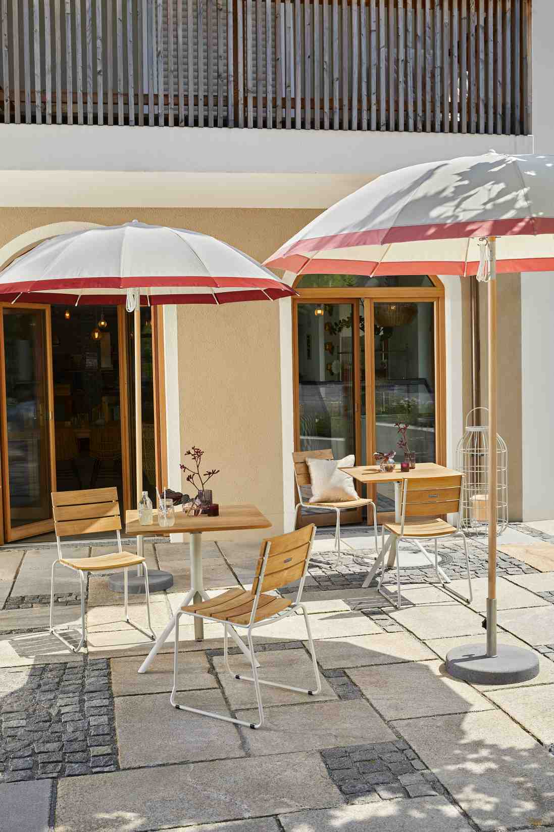 Weishäupl Pagodenschirm und Sonnenschirme mit Tischen und Stühlen für den Außenbereich auf einer Terrasse.