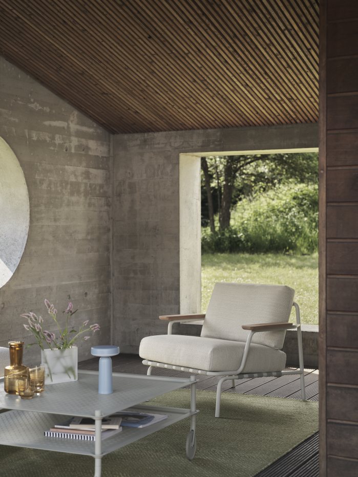 Muuto Settle Lounge Chair Outdoor Sessel in hellem Beige mit Holzelementen auf Terrasse.
