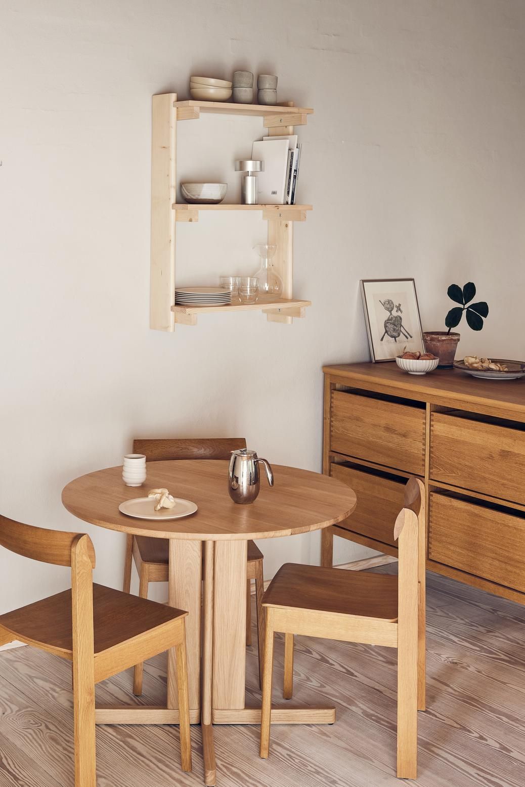 Helles Esszimmer mit rundem Holztisch, Stühlen und Beam Wandregal mit drei Fächern von Form & Refine.
