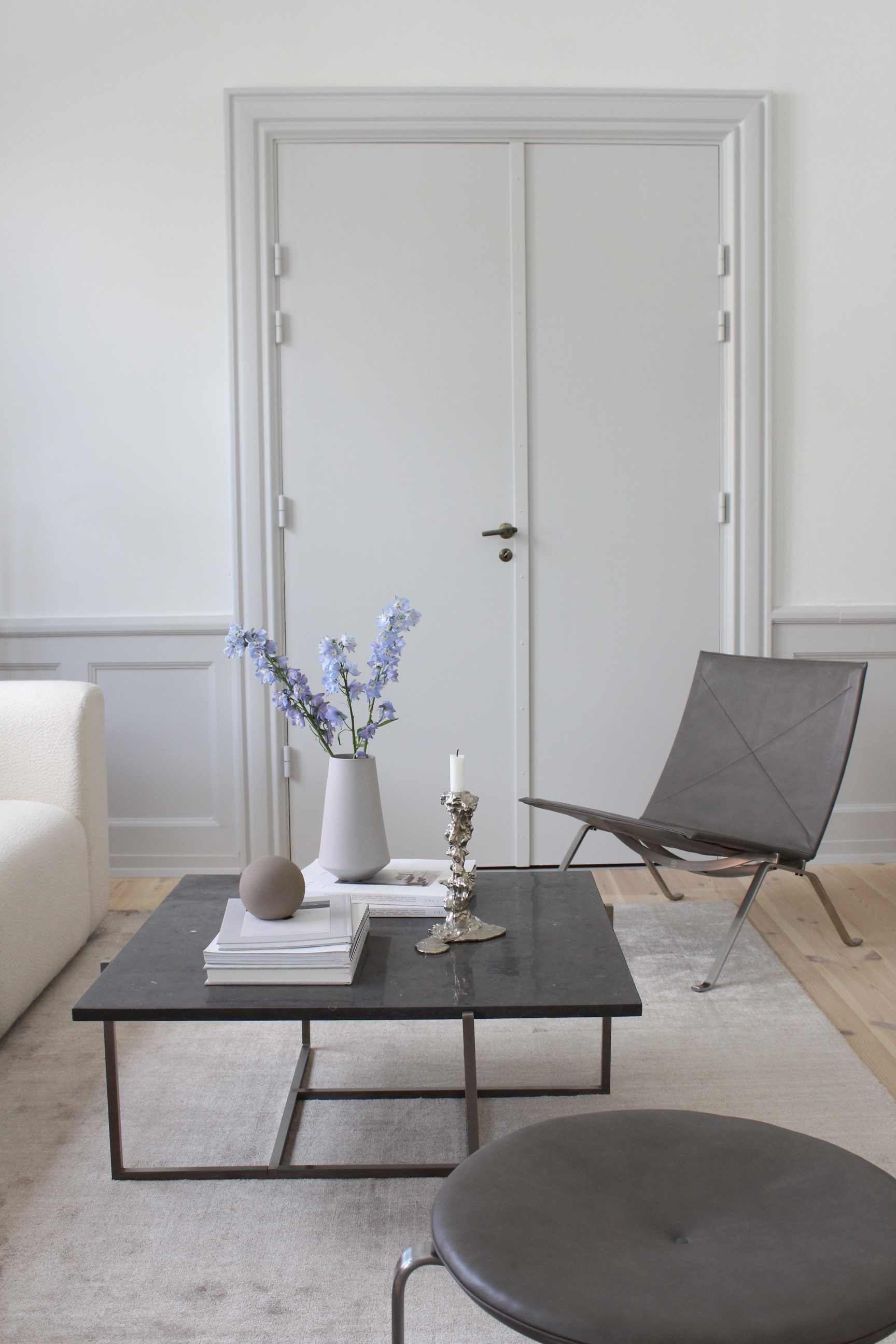Wohnzimmer-Szene mit grauem Woud Tint Rug Teppich, Couch, Sessel und Tisch mit Dekoration.