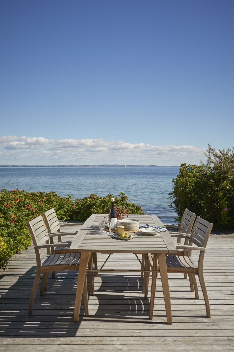 Ballare Tisch von Skagerak: Outdoor Esstisch aus Holz mit Stühlen am Meer.