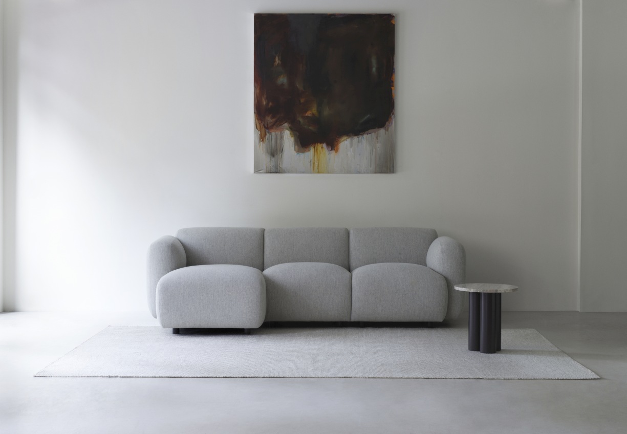 Normann Copenhagen Dit Coffee Table Beistelltisch aus Marmor neben grauem Sofa auf hellem Teppich.