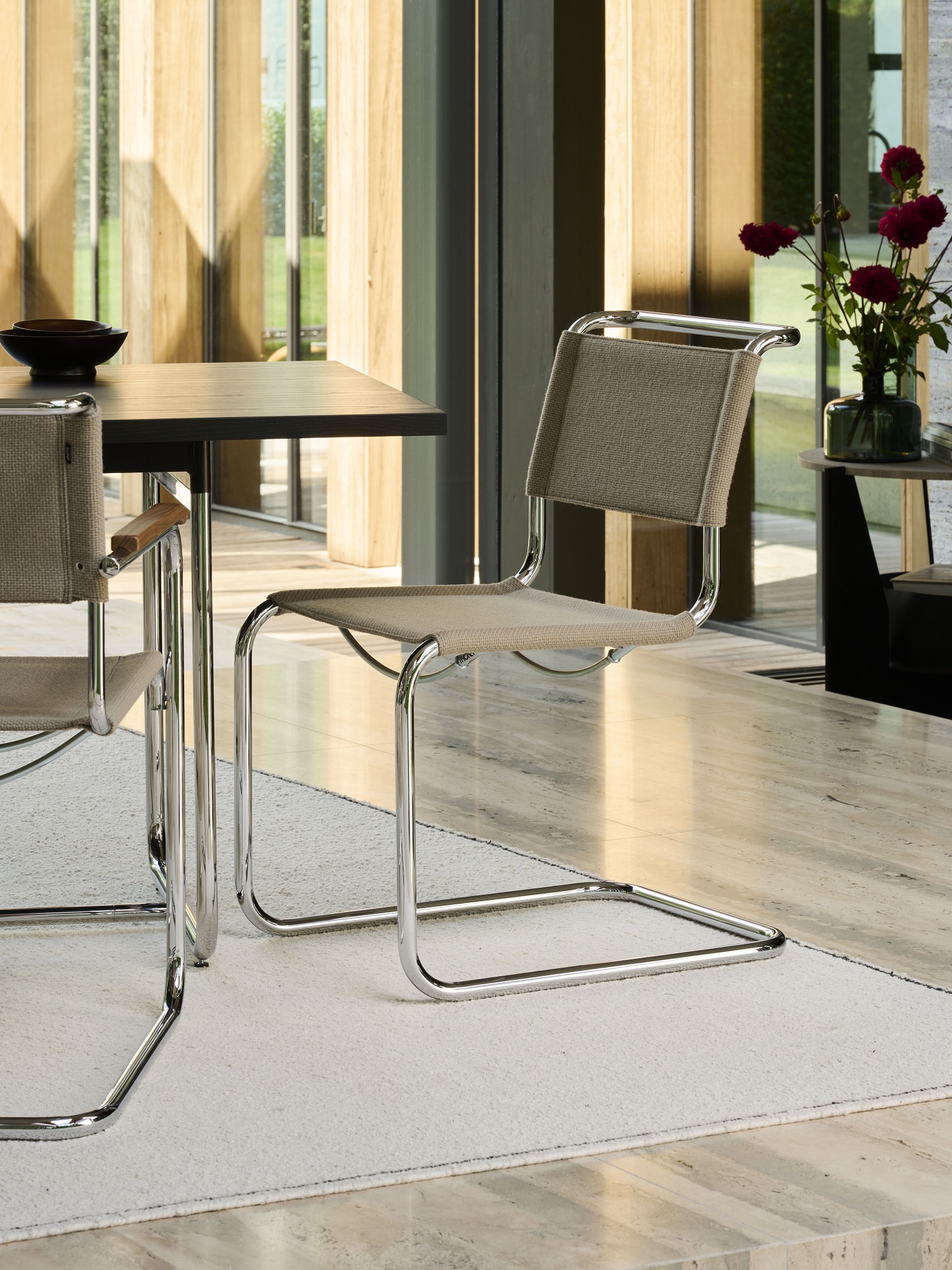 Thonet S 33 V Freischwinger Stuhl mit beigem Stoffbezug und verchromtem Stahlrohrgestell im modernen Esszimmer.