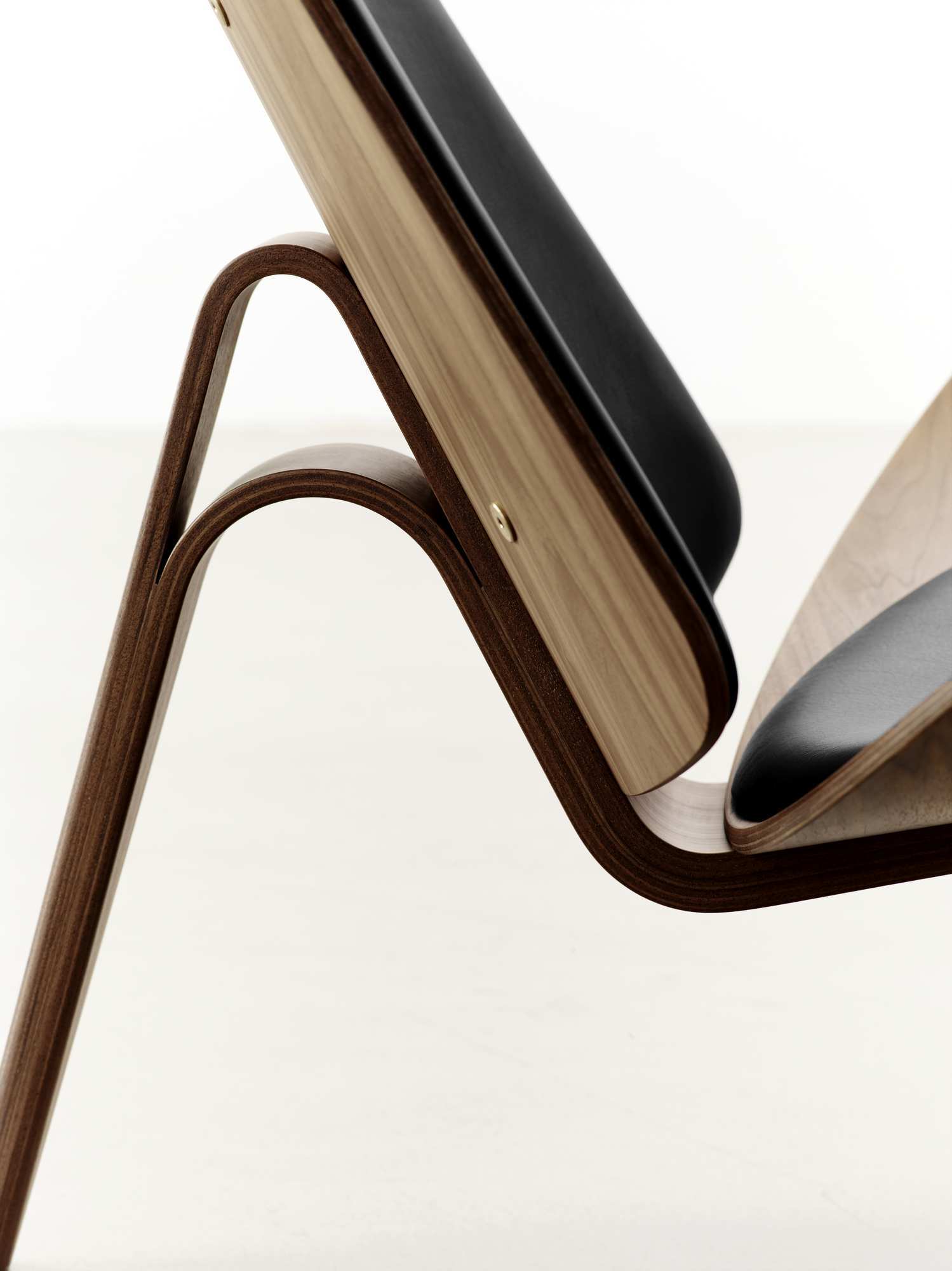 Detailaufnahme des CH07 Shell Chair Stuhls von Carl Hansen & Søn mit schwarzem Leder und Holz.