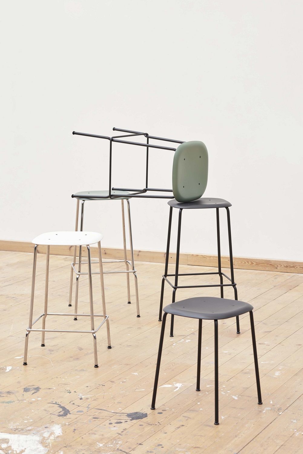 Mehrere Hay Soft Edge Hocker in Weiß, Schwarz und Grün auf einem Holzboden.