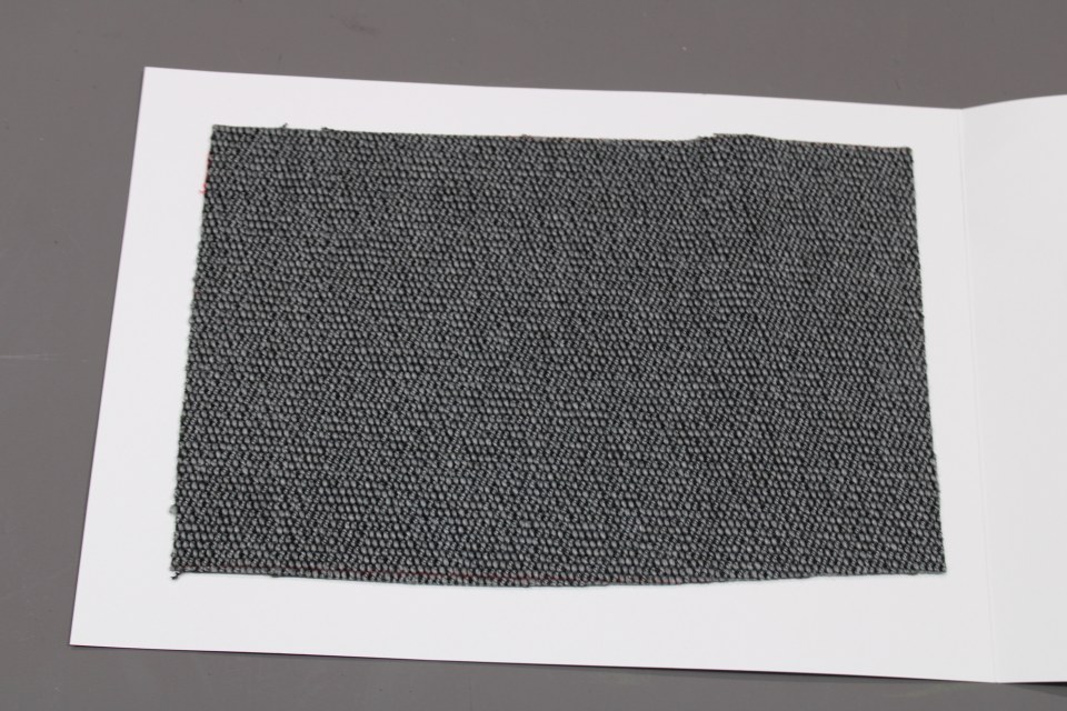 Stoffmusterkarte Gruppe 91 Cor: Nahaufnahme des grauen Möbelstoffes mit feiner Textur für Polsterarbeiten und Innendesign.