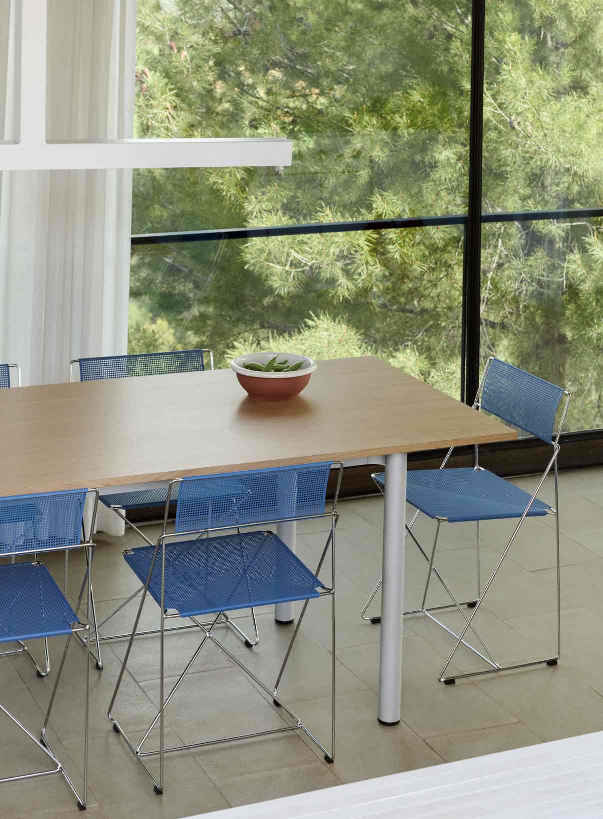 Annex Table Overhang Esstisch von Hay mit blauen Stühlen und Schale auf dem Tisch.