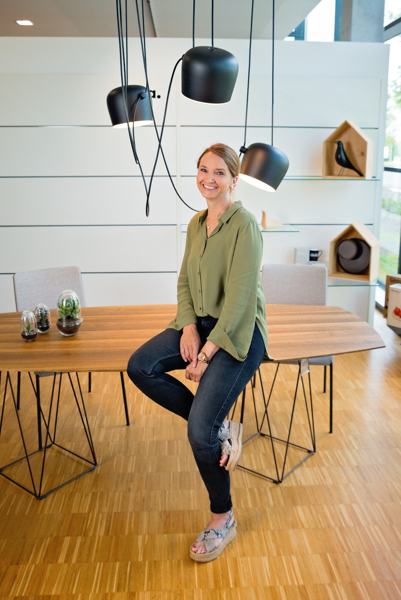 Frau sitzt unter der schwarzen Flos Aim Pendelleuchte 3er Set, moderne Hängelampe.