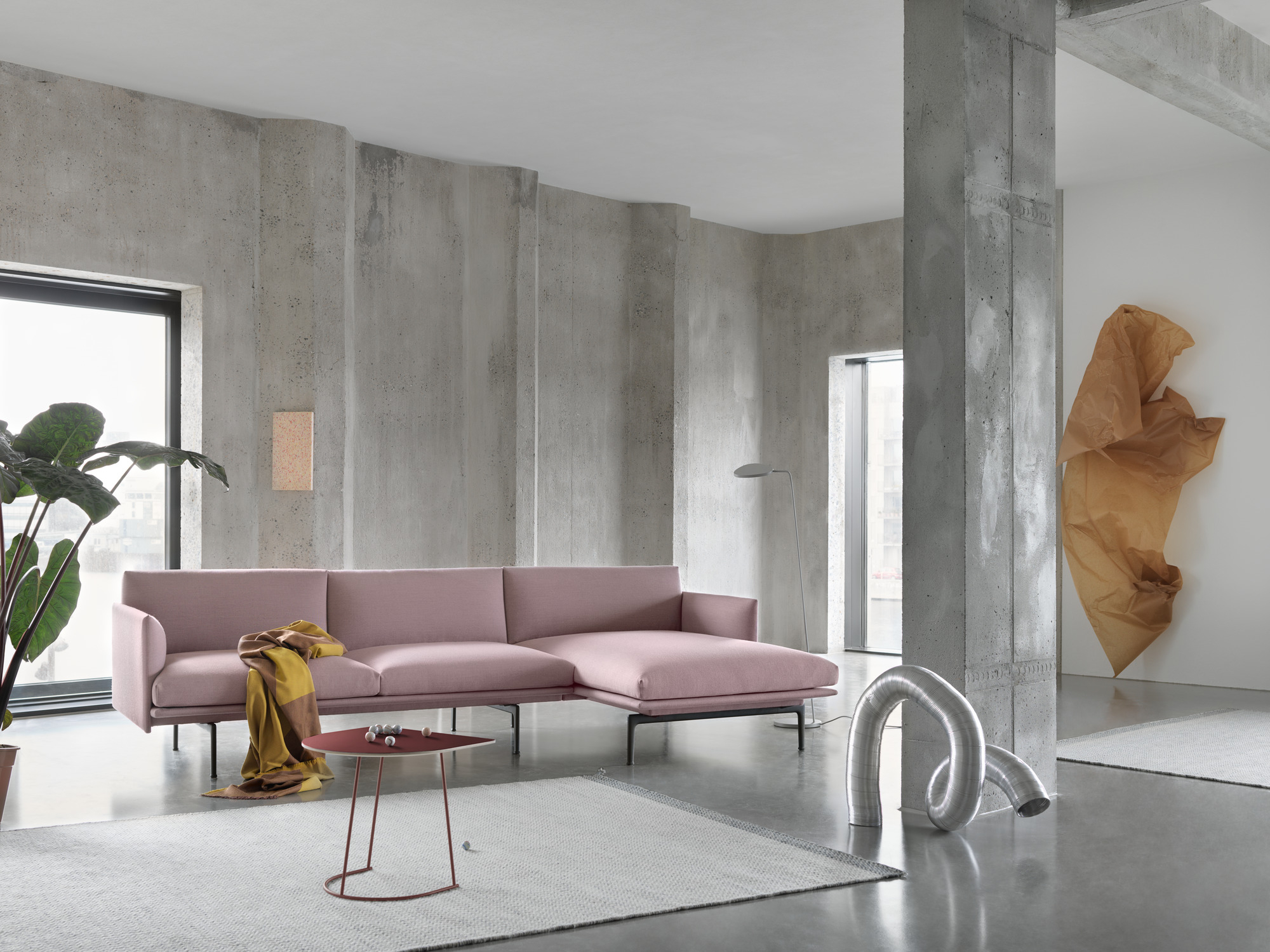 Rosa Outline Sofa mit Chaiselongue von Muuto in modernem Wohnzimmer mit Betonwänden.