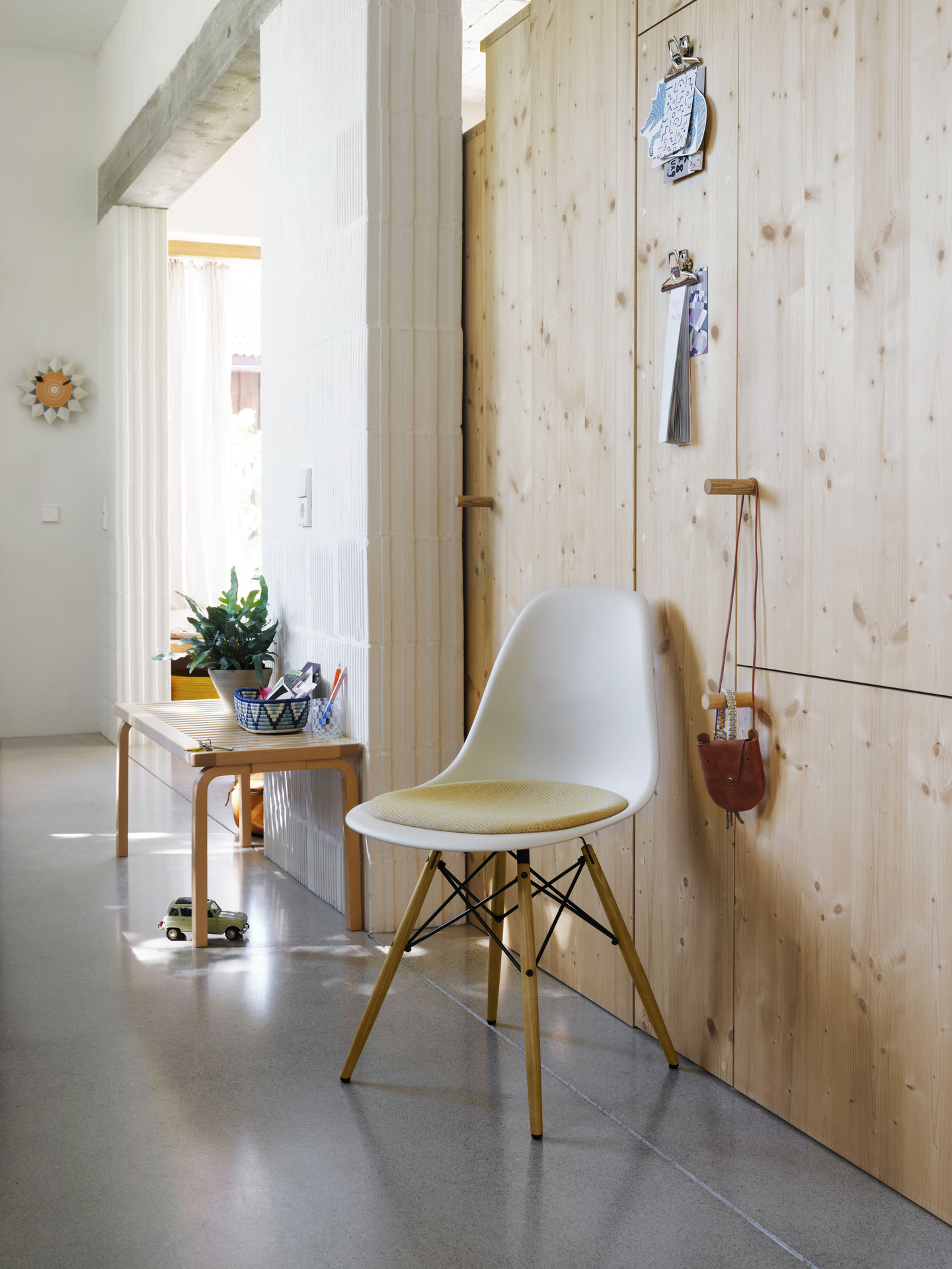 Weißer Eames Fiberglass Chair DSW Stuhl mit gelbem Sitzpolster von Vitra im modernen Flur.