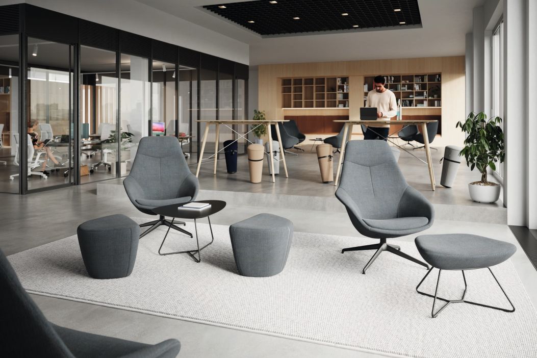 Grauer Yonda Loungesessel von Wilkhahn mit Fußhocker und kleinem Tisch in modernem Büro.