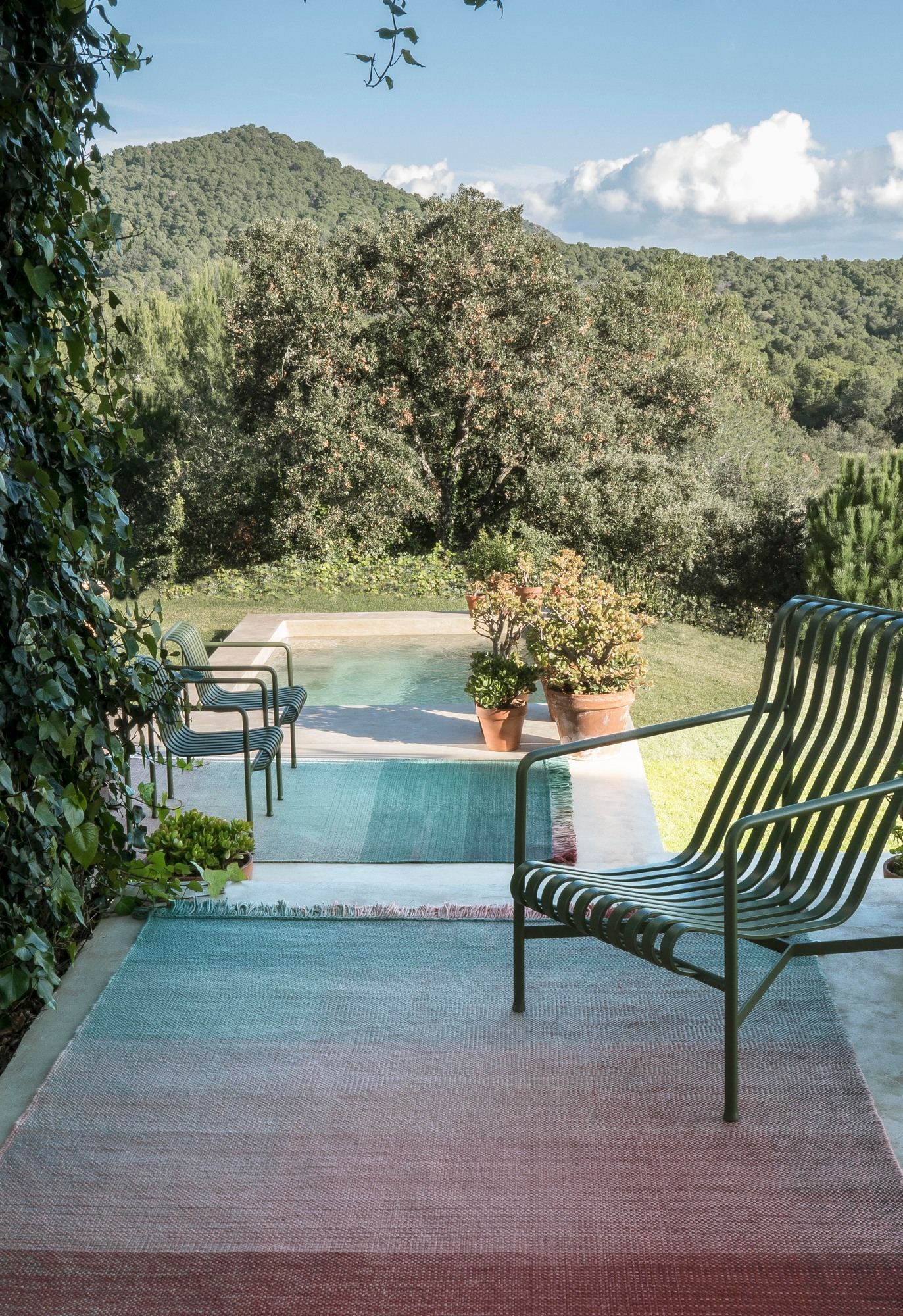 Nanimarquina Shade Outdoor Teppich, Palette 4, 170x240 cm, auf einer Terrasse mit Pool.
