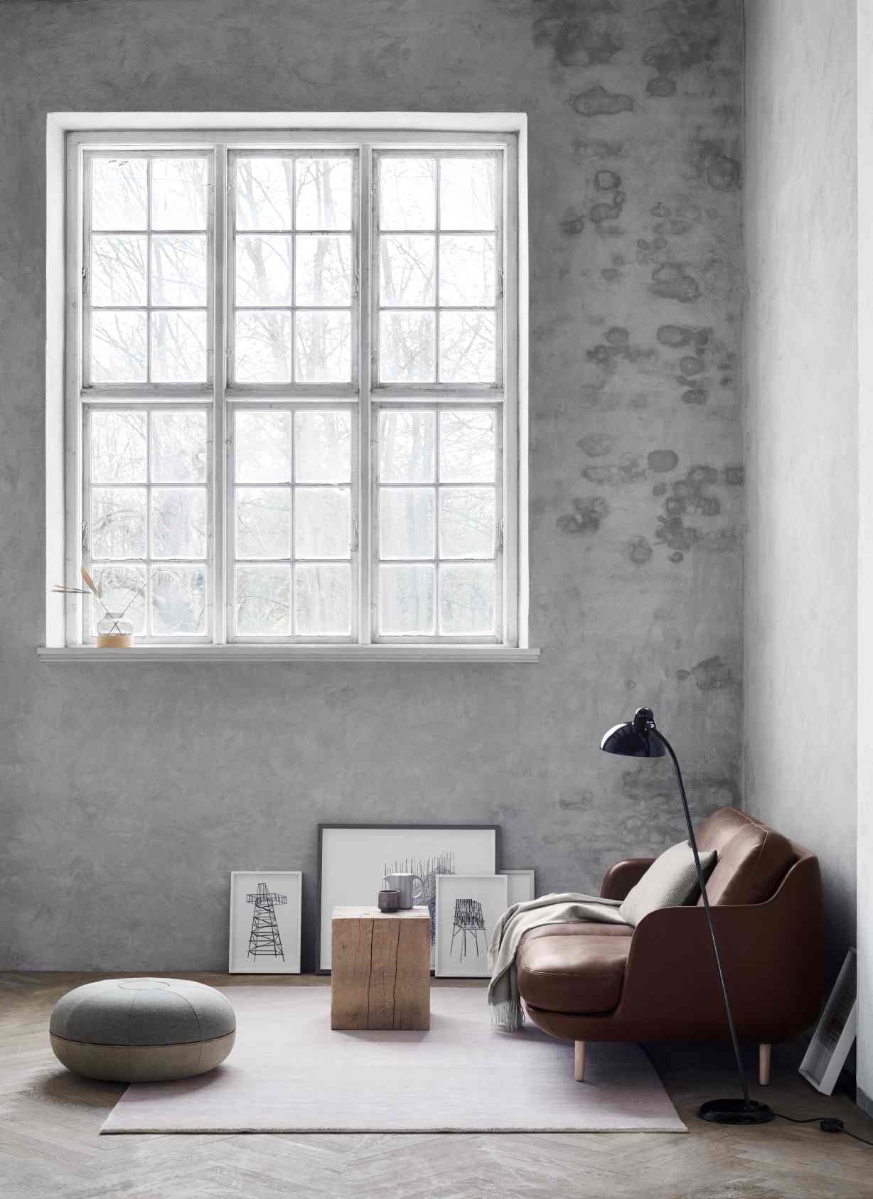 Braunes Fritz Hansen Lune Sofa in modernem Wohnzimmer mit Fenster und Betonwand.
