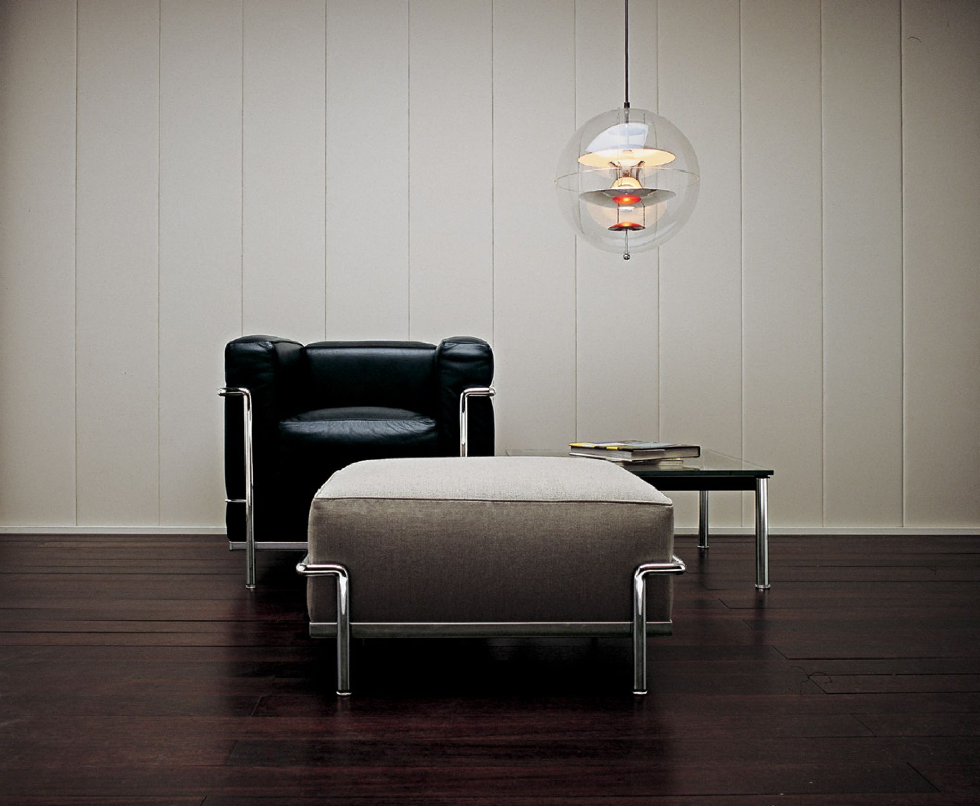 Schwarzer Ledersessel mit Hocker und Design-Hängeleuchte im Wohnzimmer, moderne Möbel für stilvolles Wohnen.