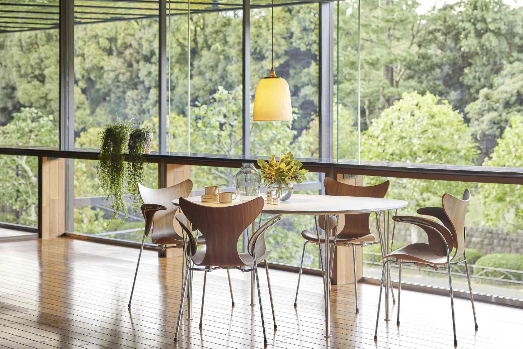 Fritz Hansen Lily Armlehnenstuhl 3208 aus Holz und Chrom in modernem Esszimmer mit Panoramafenster.