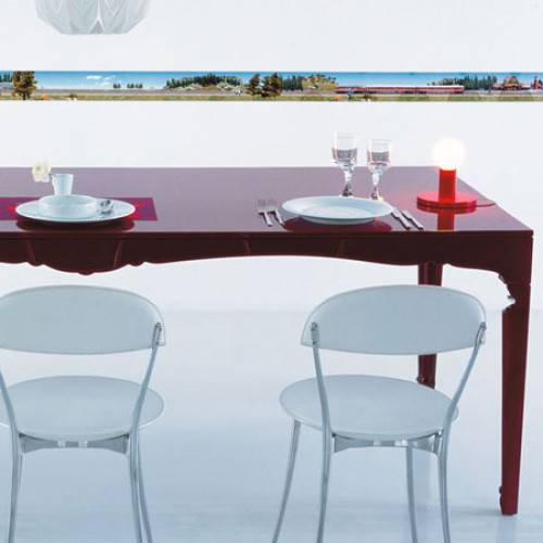 Zwei Tonietta Stühle von Zanotta an einem gedeckten Esstisch mit roter Tischplatte und moderner Lampe.
