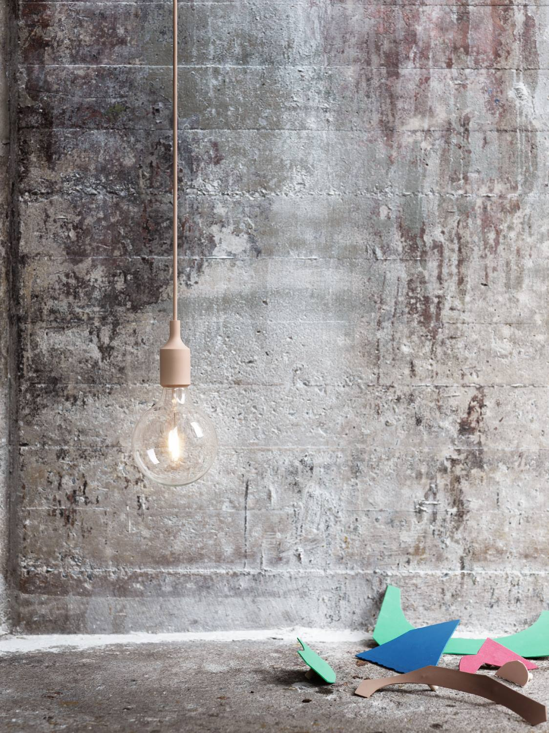 Nahaufnahme der Muuto E27 Socket Pendelleuchte mit Glühbirne vor Betonwand.