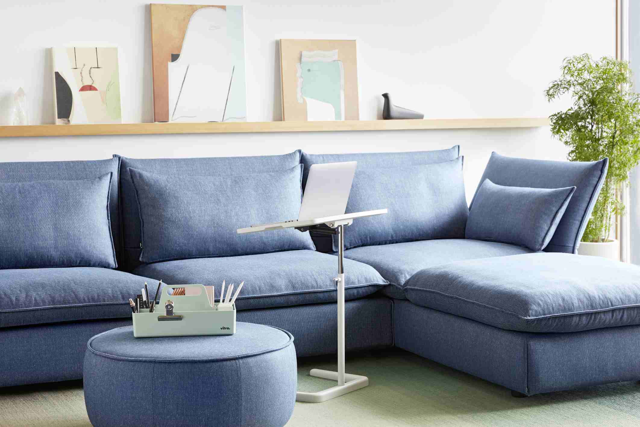 Blaues Mariposa Sofa Eckmodul von Vitra mit Laptop-Tisch und Hocker im Wohnzimmer.