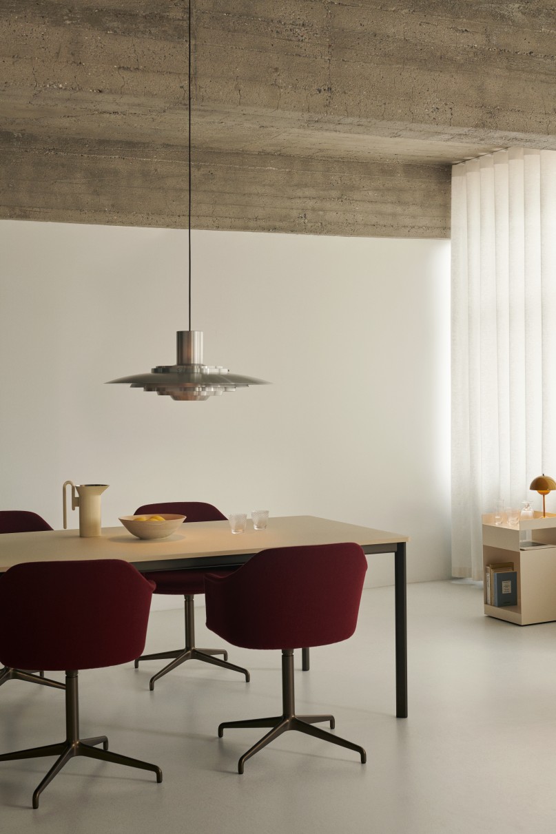 AndTradition Drip Table Esstisch mit roten Stühlen und moderner Pendelleuchte im minimalistischen Esszimmer.