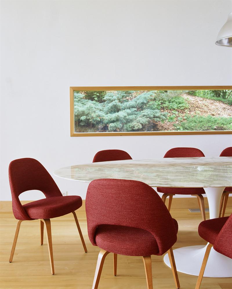 Weißes Saarinen Esstisch Untergestell von Knoll International mit runder Tischplatte und roten Stühlen in einem Esszimmer.