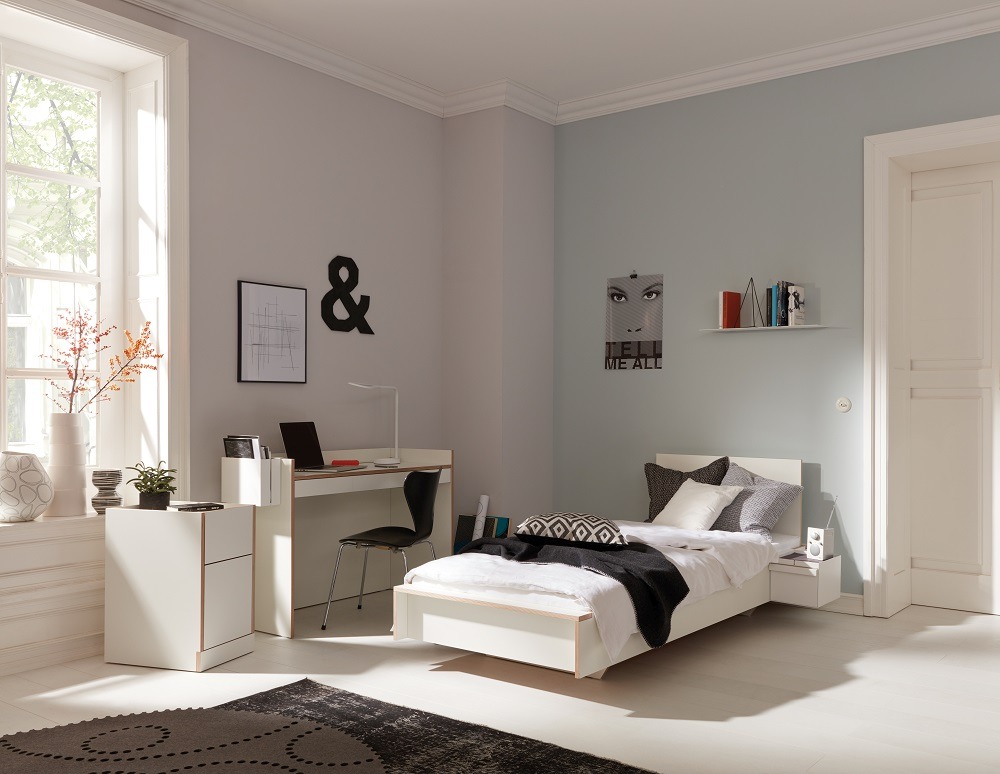 Helles Schlafzimmer mit Flai Einzelbett von Müller Möbelwerkstätten, Schreibtisch und Nachttisch in Weiß.