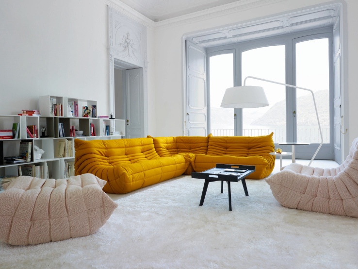 Gelbes Togo Sofa von ligne roset, einladende Wohnzimmeratmosphäre mit stilvoller Polstergarnitur und passenden Sesseln.